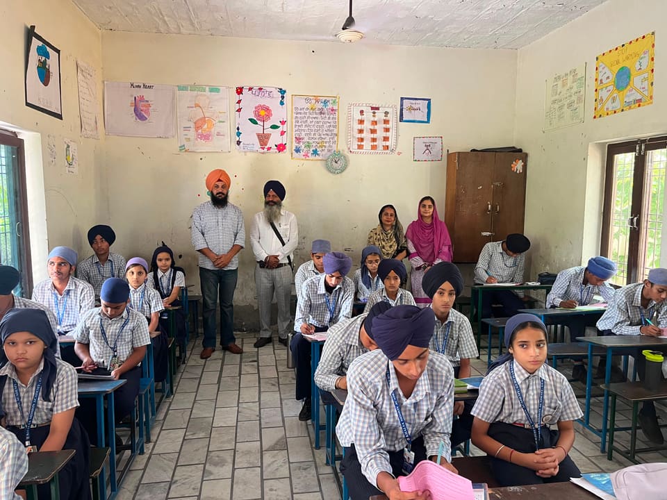 Students at their desks working while teachers observe